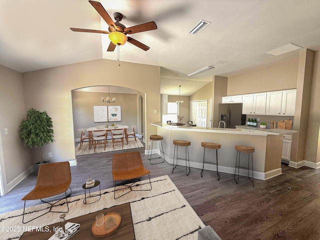 living room with vaulted ceiling, dark wood finished floors, arched walkways, ceiling fan, and baseboards