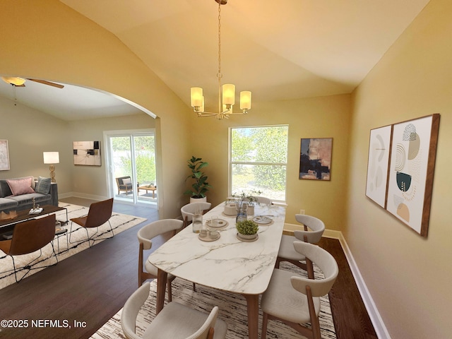 dining room featuring lofted ceiling, dark wood-style floors, arched walkways, a chandelier, and baseboards