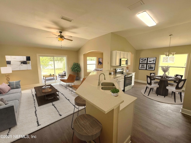 living area featuring dark wood-style flooring, arched walkways, baseboards, vaulted ceiling, and a ceiling fan