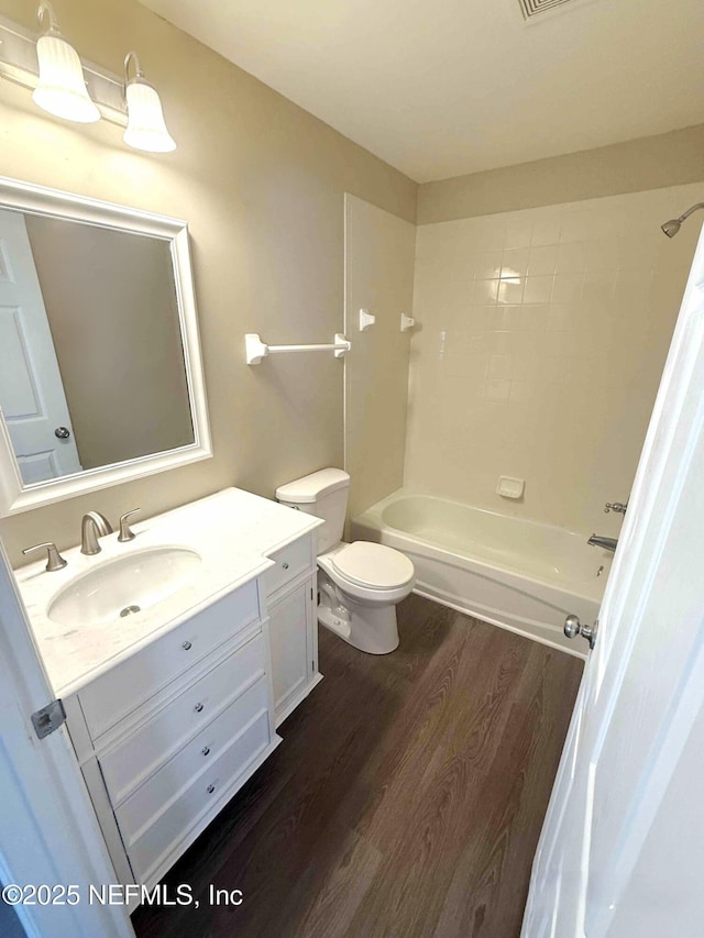 bathroom with wood finished floors, vanity, toilet, and shower / tub combination