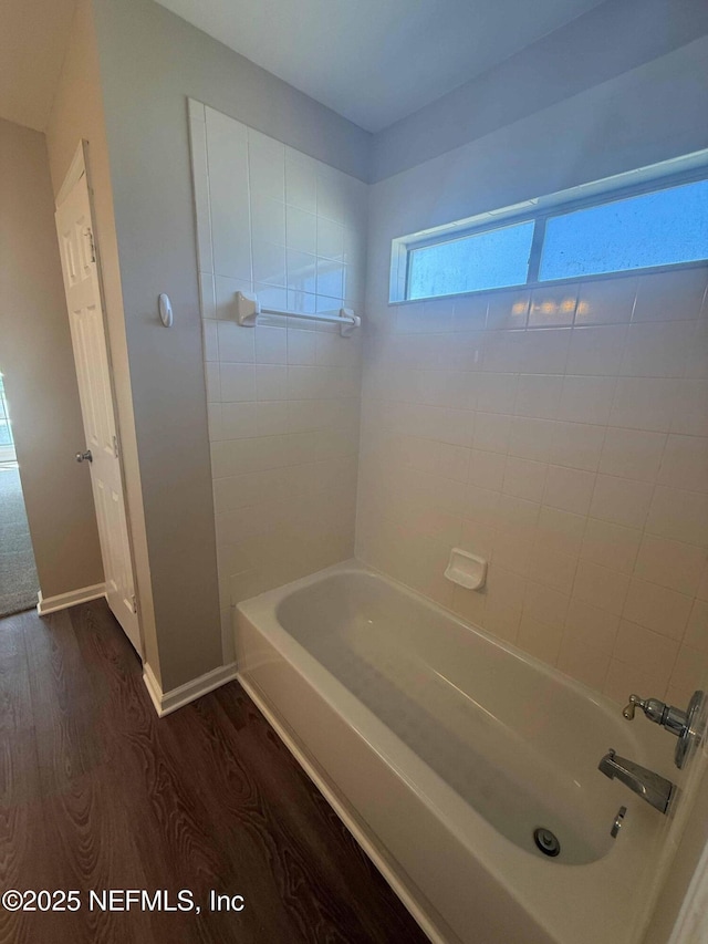 bathroom with wood finished floors, shower / bath combination, and baseboards