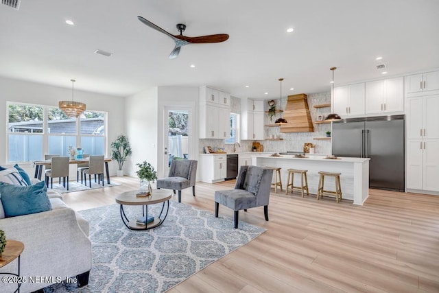 living room with a ceiling fan, light wood-style floors, and recessed lighting