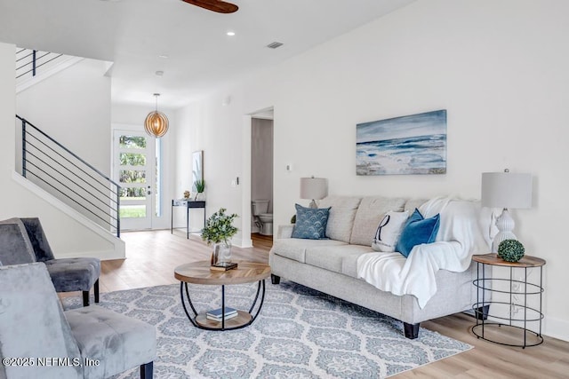 living area with stairway, wood finished floors, baseboards, recessed lighting, and ceiling fan