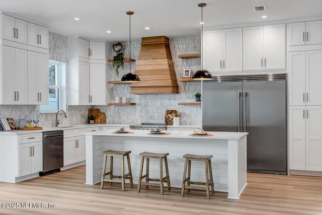 kitchen featuring open shelves, stainless steel appliances, light countertops, a kitchen island, and recessed lighting