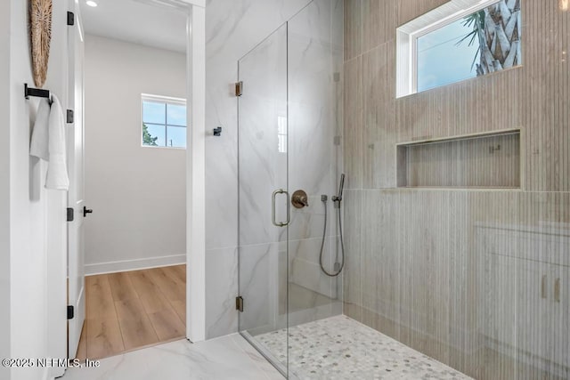 full bath with a stall shower, baseboards, and wood finished floors