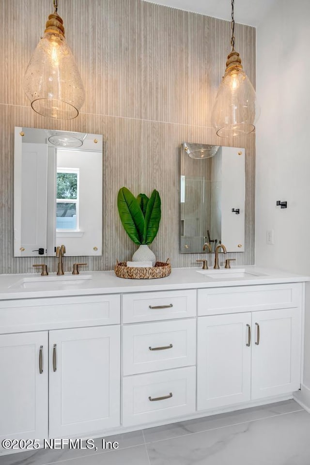 bathroom with double vanity, marble look tile flooring, and a shower