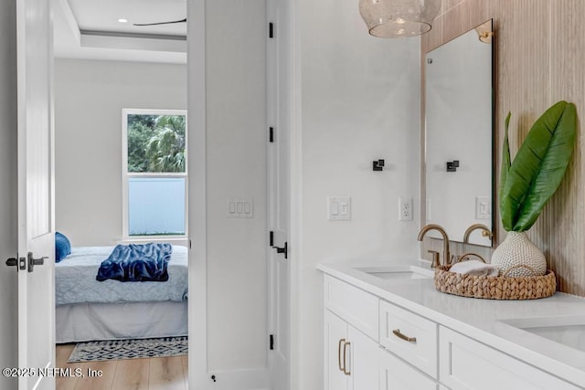 bathroom with connected bathroom, double vanity, and wood finished floors