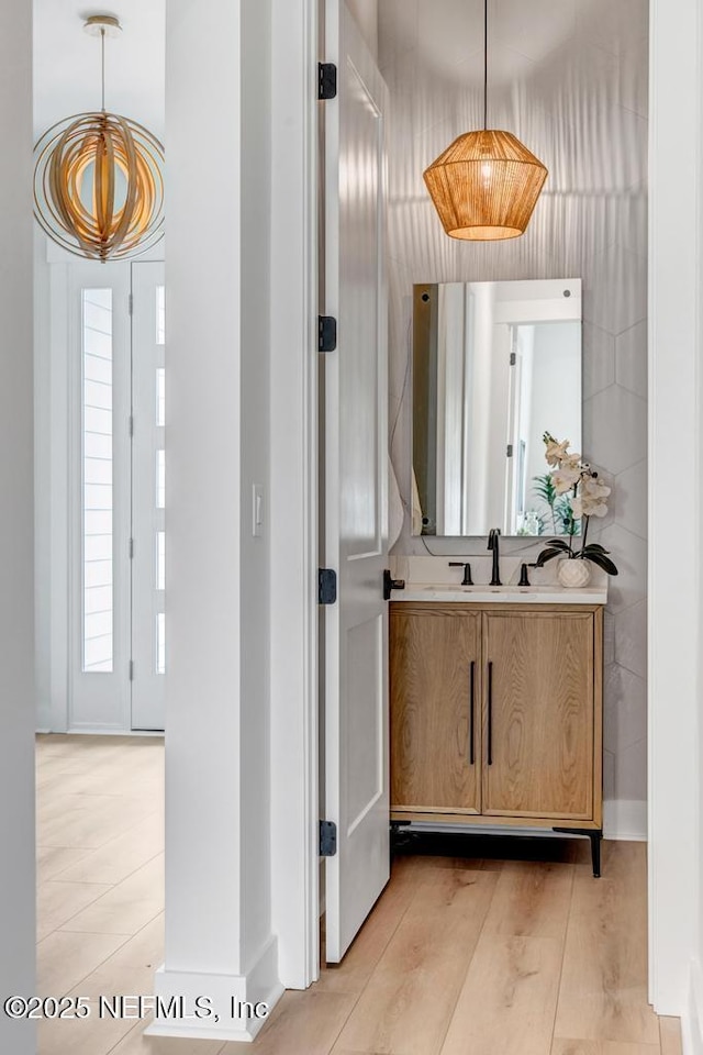 hallway with a sink, a chandelier, and light wood-style flooring