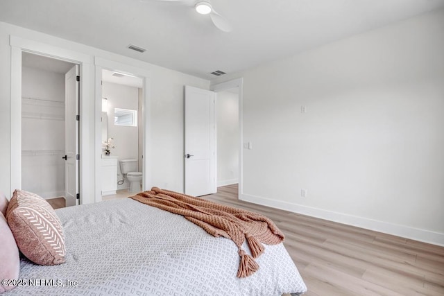 bedroom featuring light wood-type flooring, a spacious closet, baseboards, and a closet