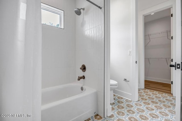 full bathroom featuring toilet, shower / bath combination with curtain, a walk in closet, and baseboards