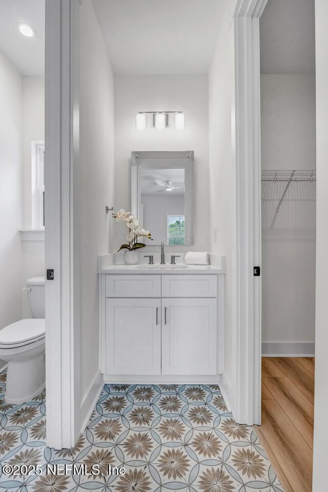bathroom featuring tile patterned floors, vanity, toilet, baseboards, and a spacious closet