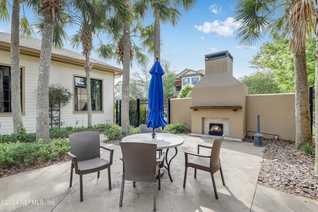 12700 Bartram Park Blvd Unit 123, Jacksonville, FL 32258 - view of patio featuring a lit fireplace, fence, and outdoor dining space