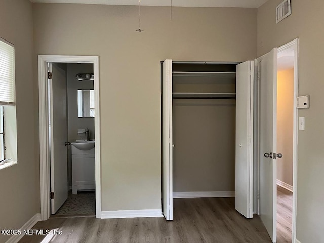 10258 Elmhurst Dr, Jacksonville, FL 32218 - unfurnished bedroom featuring wood finished floors, a closet, baseboards, a sink, and ensuite bathroom