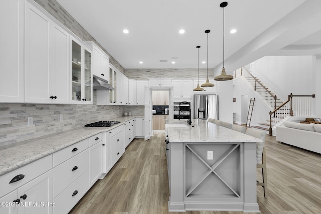 94 Anthem Ridge Dr, Ponte Vedra, FL 32081 - kitchen with stainless steel refrigerator with ice dispenser, gas cooktop, light wood-style floors, backsplash, and glass insert cabinets