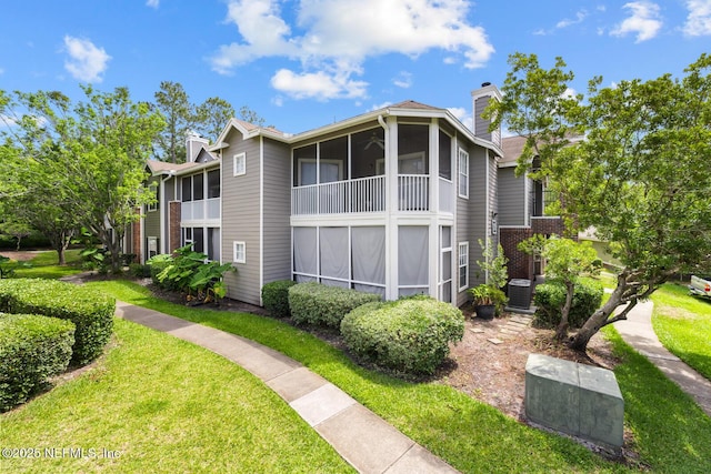 10000 Gate Pkwy Unit 2123, Jacksonville, FL 32246 - view of side of property featuring cooling unit, a chimney, a sunroom, brick siding, and a yard