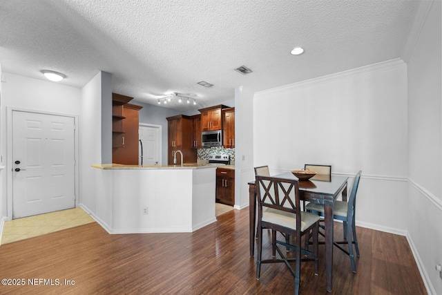 10000 Gate Pkwy Unit 2123, Jacksonville, FL 32246 - kitchen with stainless steel microwave, a sink, backsplash, dark wood-style flooring, and a peninsula