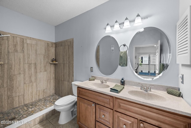 10000 Gate Pkwy Unit 2123, Jacksonville, FL 32246 - full bathroom featuring toilet, tile patterned flooring, a tile shower, double vanity, and a textured ceiling