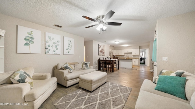 11428 Rustic Pines Cir E, Jacksonville, FL 32257 - living room with a ceiling fan, a textured wall, a textured ceiling, and light wood finished floors