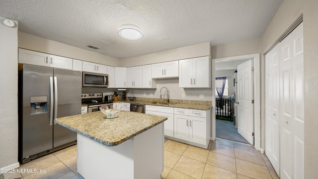 11428 Rustic Pines Cir E, Jacksonville, FL 32257 - kitchen with appliances with stainless steel finishes, a sink, white cabinetry, a kitchen island, and a textured ceiling