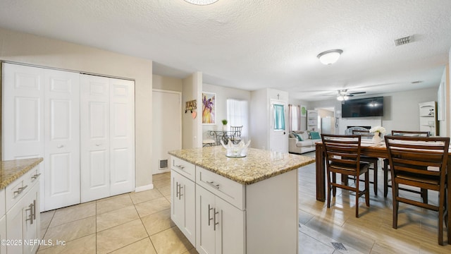 11428 Rustic Pines Cir E, Jacksonville, FL 32257 - kitchen with ceiling fan, a center island, open floor plan, a textured ceiling, and white cabinetry