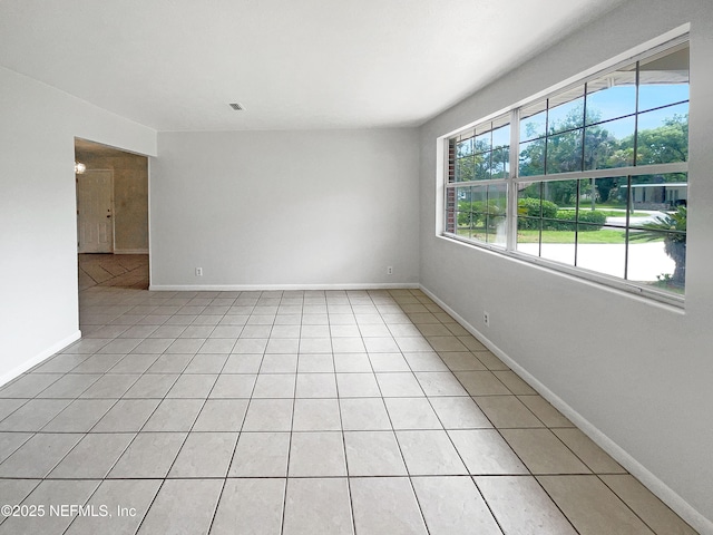 spare room with light tile patterned floors and baseboards