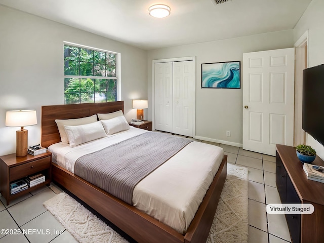 bedroom with light tile patterned floors, a closet, and baseboards