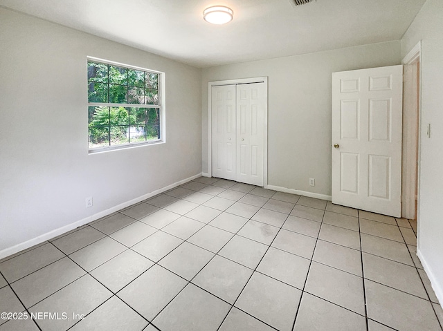 unfurnished bedroom featuring light tile patterned floors, a closet, and baseboards