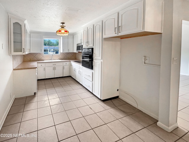 kitchen featuring black appliances, tasteful backsplash, a sink, white cabinets, and glass insert cabinets