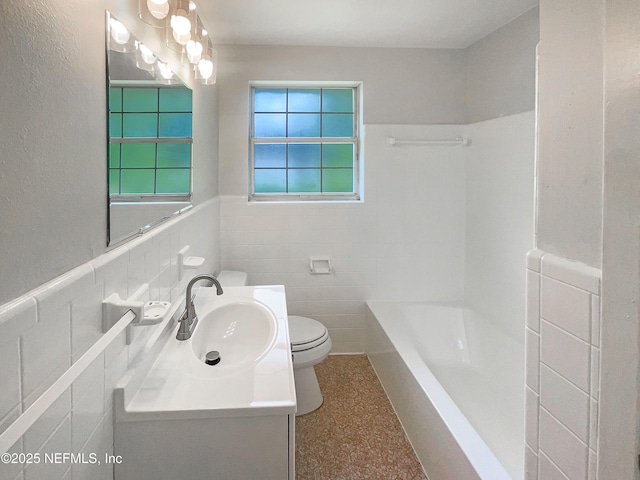 bathroom featuring toilet, tile walls, vanity, wainscoting, and shower / tub combination