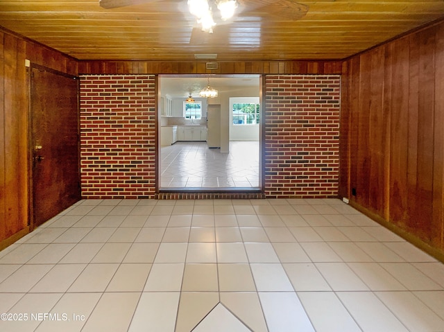 tiled spare room featuring wooden ceiling, wooden walls, and brick wall
