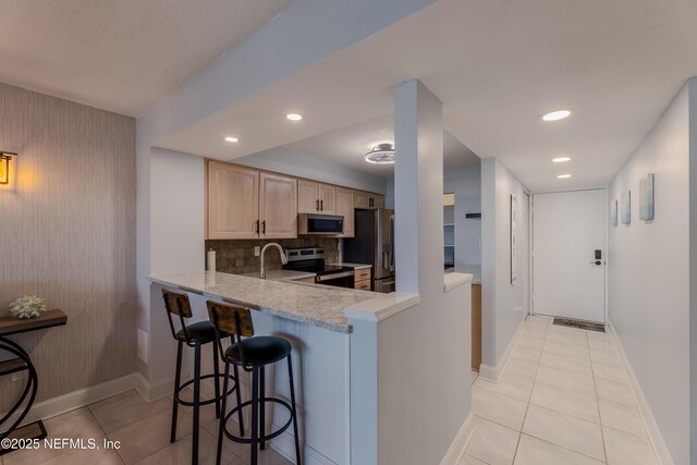 1301 1st St S Unit 1403, Jacksonville Beach, FL 32250 - kitchen with stainless steel appliances, light brown cabinets, light tile patterned flooring, baseboards, and recessed lighting