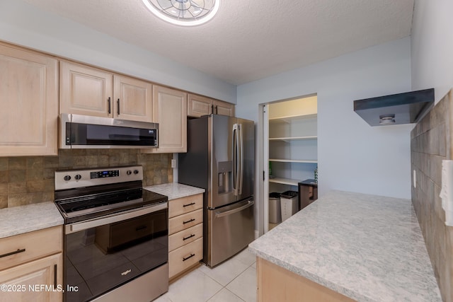 1301 1st St S Unit 1403, Jacksonville Beach, FL 32250 - kitchen featuring stainless steel appliances, light brown cabinetry, tasteful backsplash, light tile patterned floors, and a textured ceiling