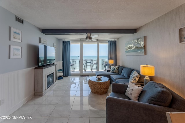 1301 1st St S Unit 1403, Jacksonville Beach, FL 32250 - living room with beam ceiling, a glass covered fireplace, ceiling fan, a textured ceiling, and light tile patterned floors