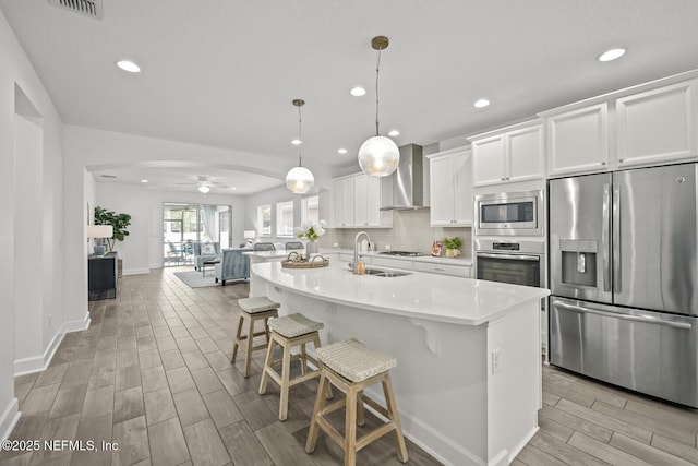 107 Park Lake Dr, Ponte Vedra, FL 32081 - kitchen with appliances with stainless steel finishes, a sink, wall chimney range hood, wood tiled floors, and a kitchen breakfast bar
