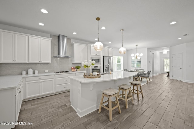 107 Park Lake Dr, Ponte Vedra, FL 32081 - kitchen with wall chimney range hood, stainless steel appliances, decorative backsplash, a center island with sink, and a kitchen breakfast bar