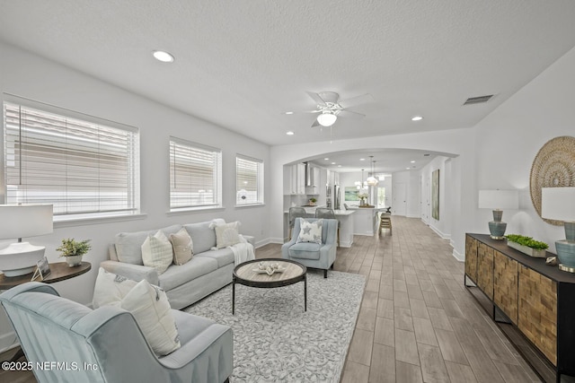 107 Park Lake Dr, Ponte Vedra, FL 32081 - living room with arched walkways, a ceiling fan, light wood-style flooring, a textured ceiling, and a chandelier