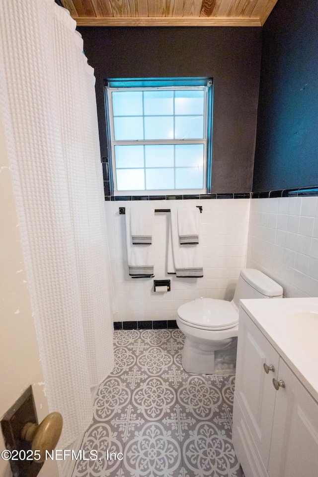 1525 E Call St, Starke, FL 32091 - bathroom featuring toilet, tile patterned flooring, tile walls, curtained shower, and a wainscoted wall