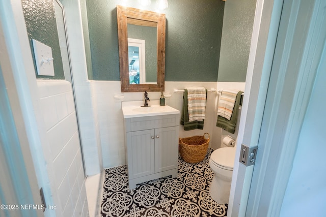 1525 E Call St, Starke, FL 32091 - bathroom with toilet, a wainscoted wall, vanity, tile walls, and tile patterned floors
