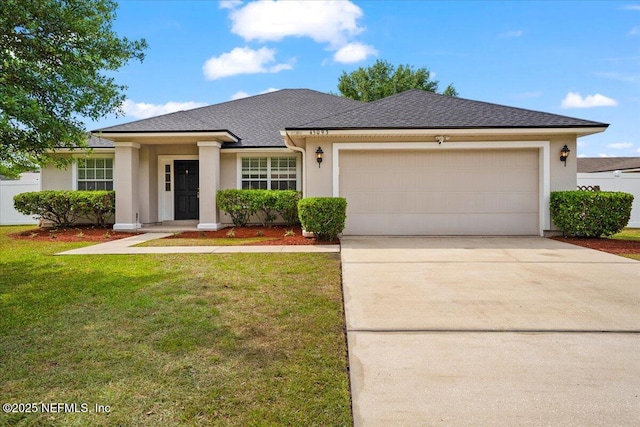 view of front of house with concrete driveway, a garage, a front lawn, and stucco siding