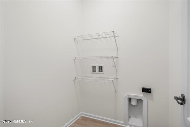 clothes washing area featuring hookup for a washing machine, wood finished floors, and baseboards