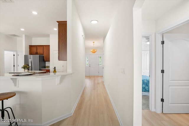 corridor featuring light wood-style flooring, baseboards, and recessed lighting