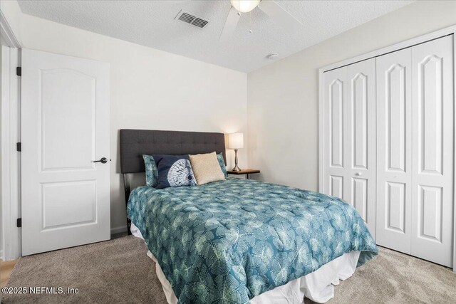 carpeted bedroom featuring a closet, a textured ceiling, and a ceiling fan