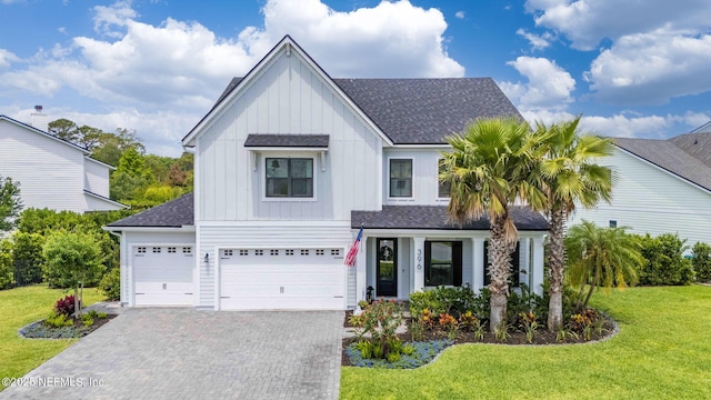 view of front of house with board and batten siding, roof with shingles, a front lawn, decorative driveway, and an attached garage