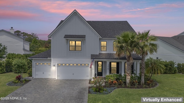 view of front facade featuring board and batten siding, a front lawn, decorative driveway, a shingled roof, and an attached garage