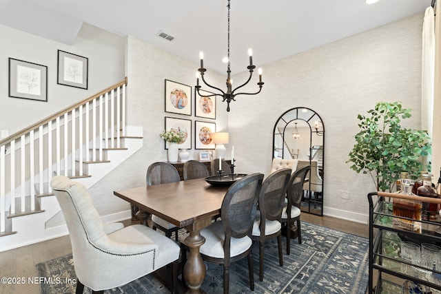 dining space featuring baseboards, wood finished floors, stairway, and a chandelier