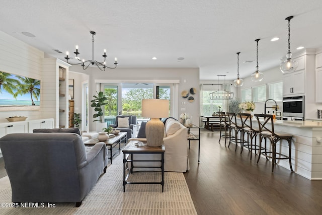 living room featuring a chandelier, dark wood-type flooring, healthy amount of natural light, and recessed lighting