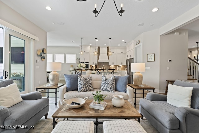 living room featuring a chandelier, baseboards, recessed lighting, and stairs