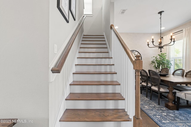 stairs with a chandelier and wood finished floors