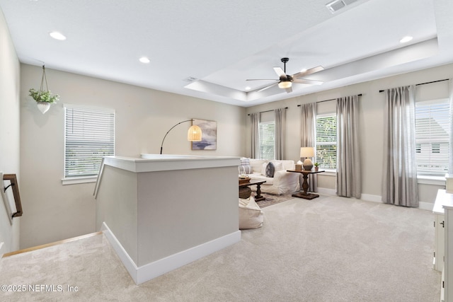 carpeted living area with a ceiling fan, recessed lighting, baseboards, and a tray ceiling