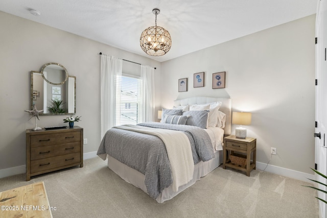 bedroom with a chandelier, light carpet, and baseboards
